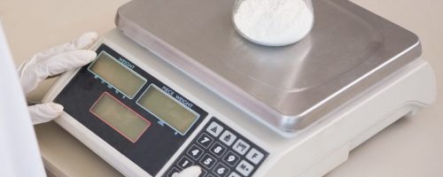 Scientist weighing beaker with white powder inside